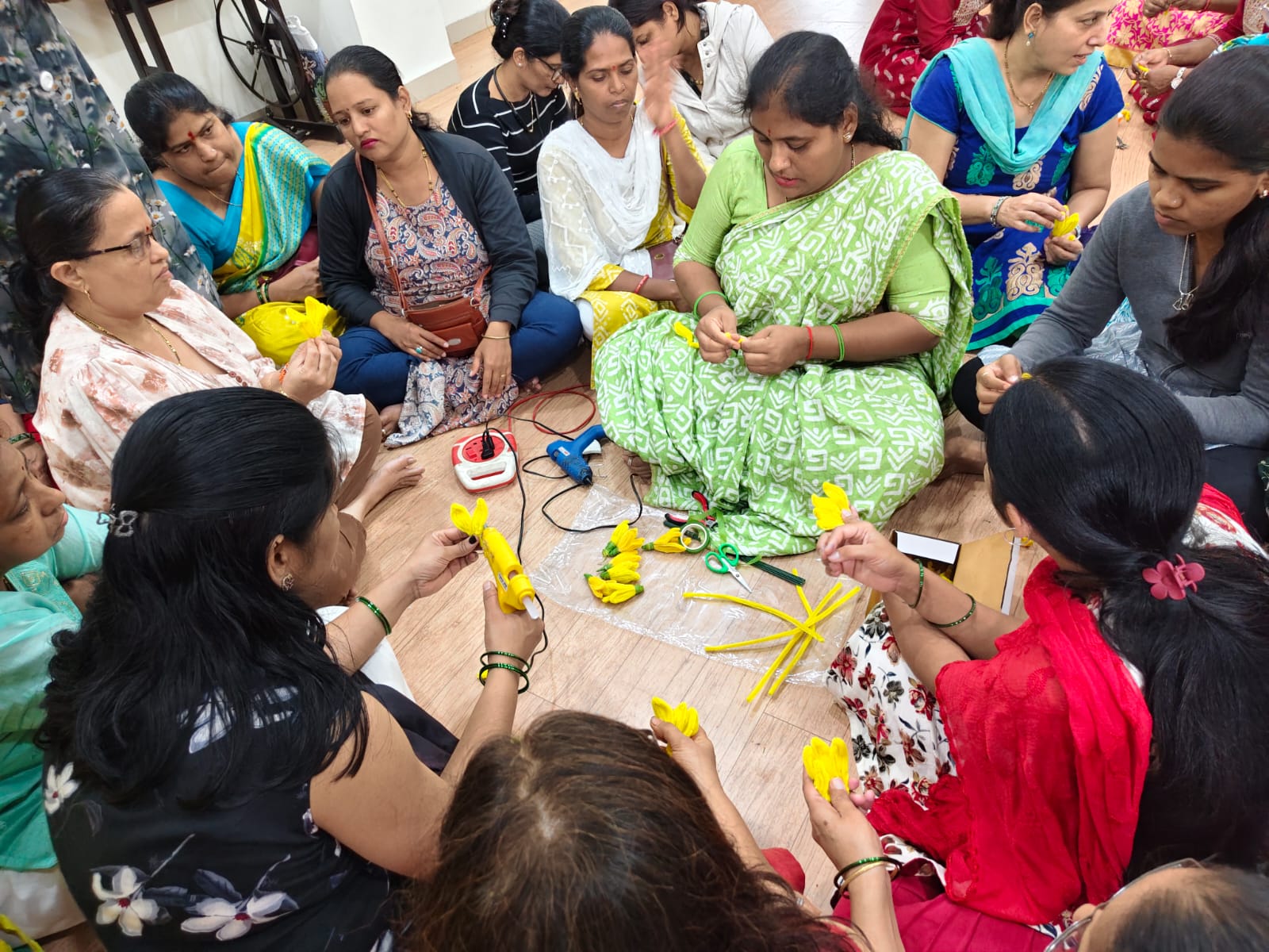 Close view of women working with a glue gun and yellow flower petals
