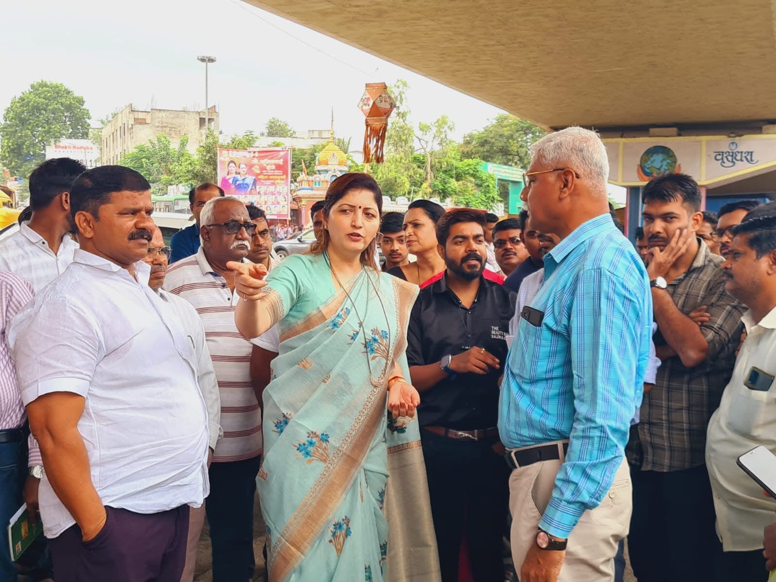 Woman in a saree pointing while officials and residents listen during a field inspection