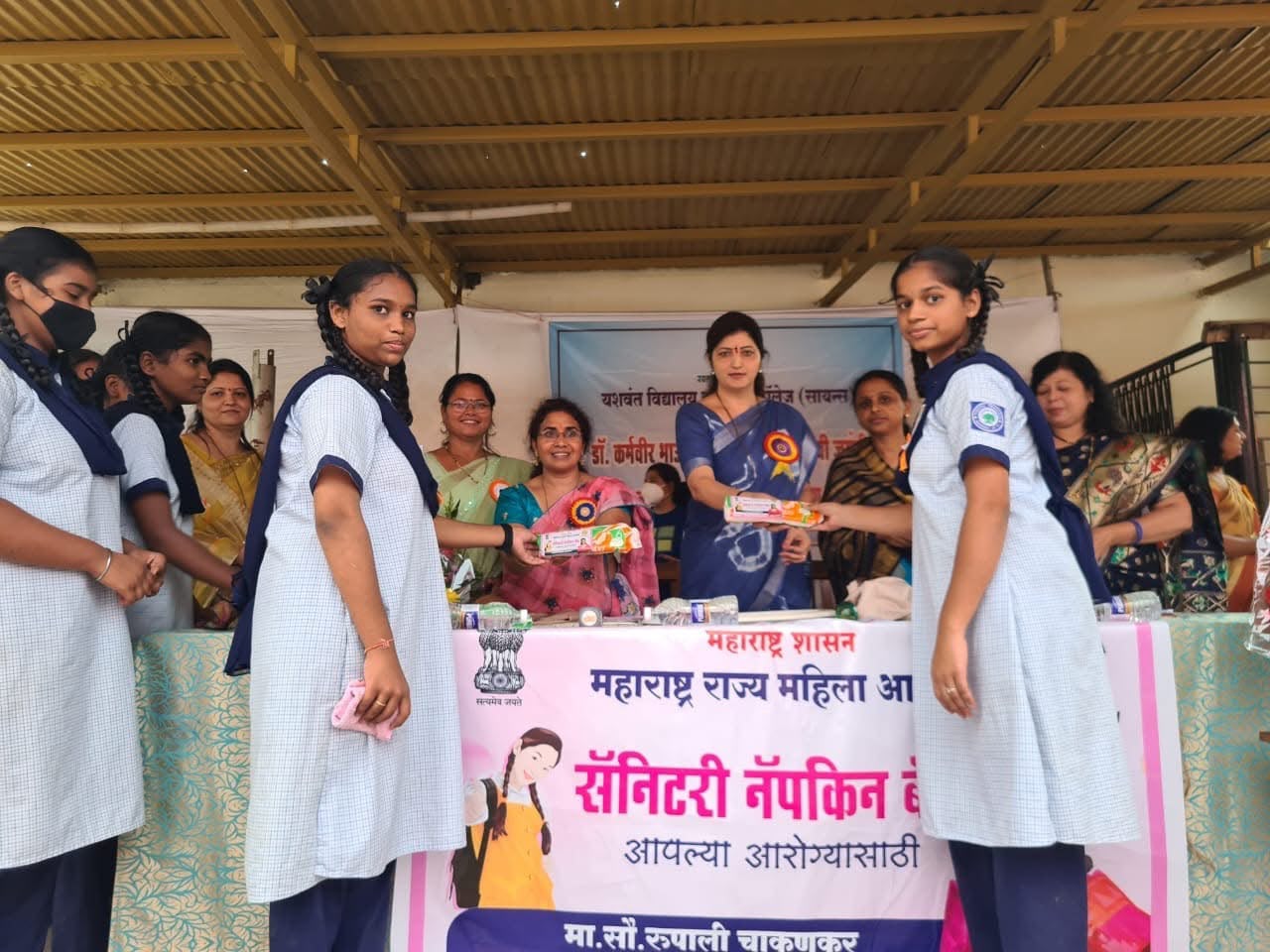 Schoolgirls receiving sanitary napkin packs at a school programme