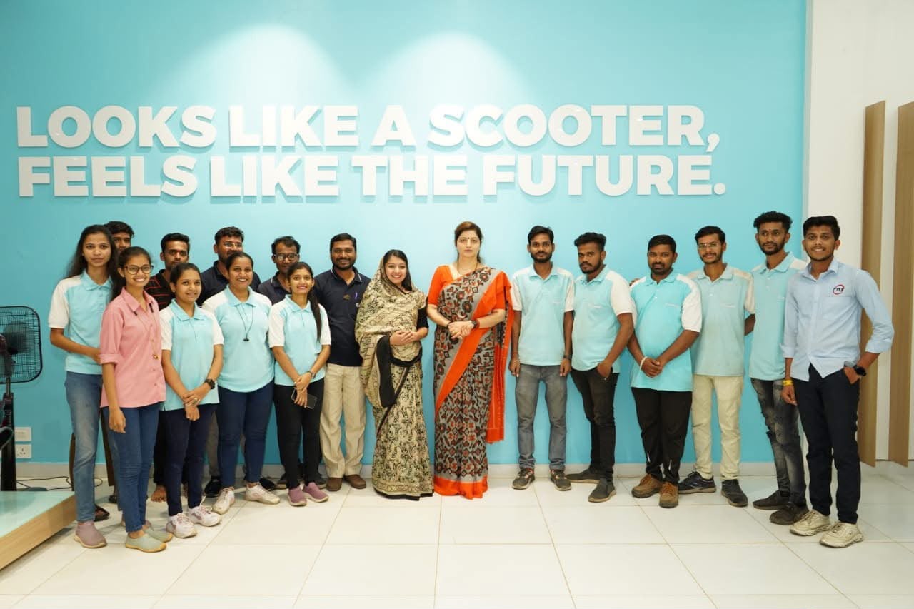 Group photograph with young factory staff in front of a company wall graphic