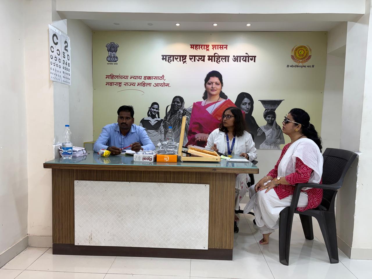 Eye camp desk with vision chart and volunteers registering a woman