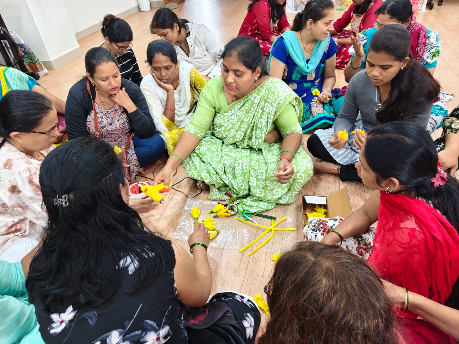 Women learning flower-making in a circle at the Pune centre