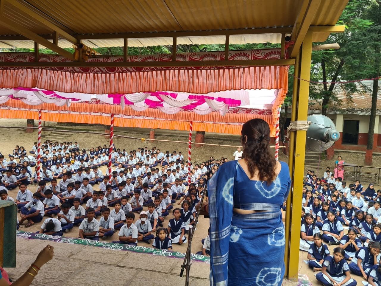 Speaker addressing hundreds of school students seated in a ground assembly