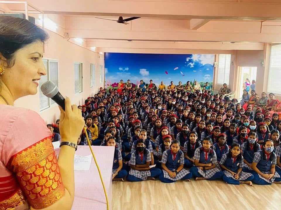 Speaker addressing hundreds of schoolgirls seated in a school hall