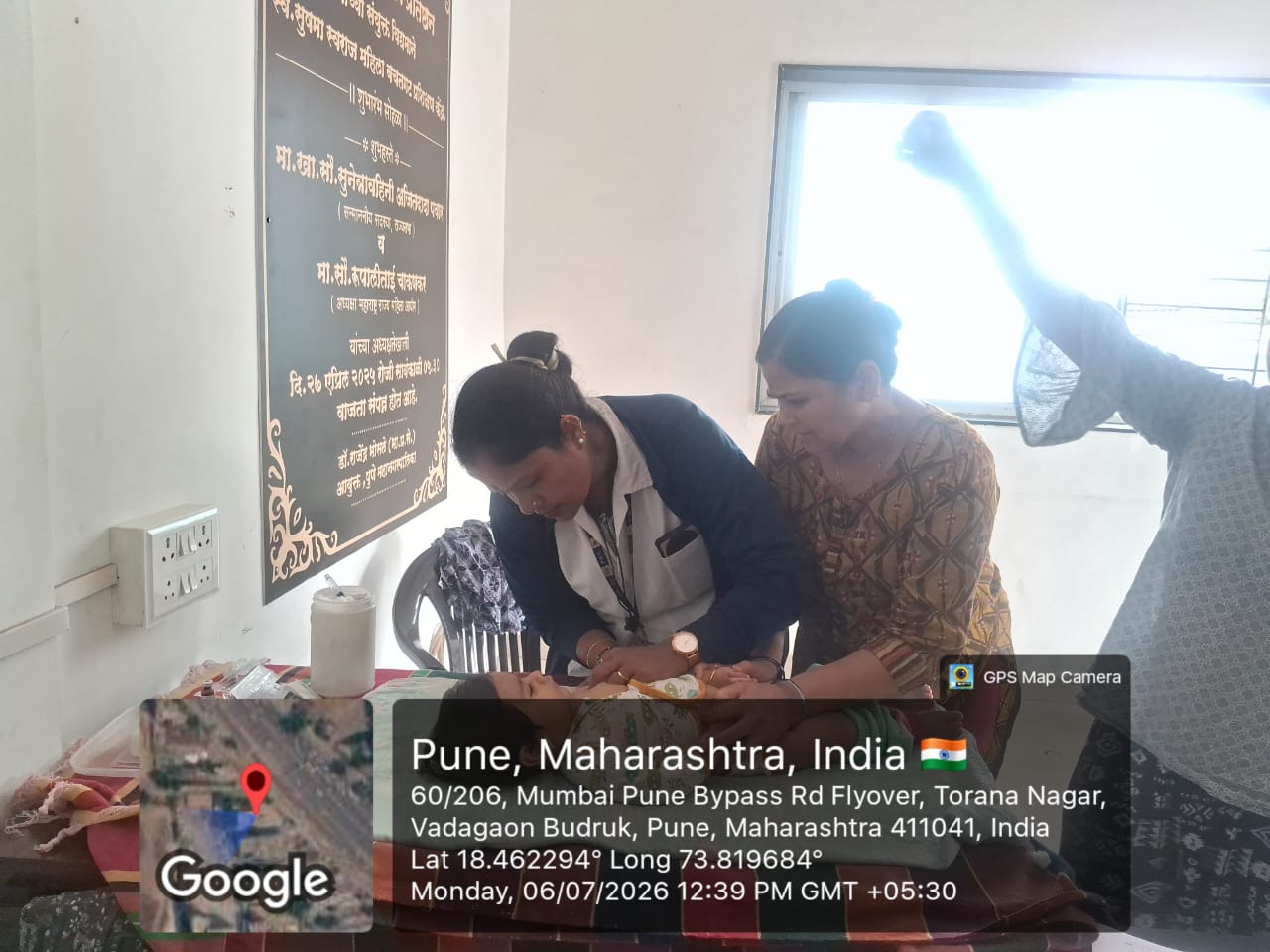 Nurse attending to an infant on a examination bed with the mother beside her