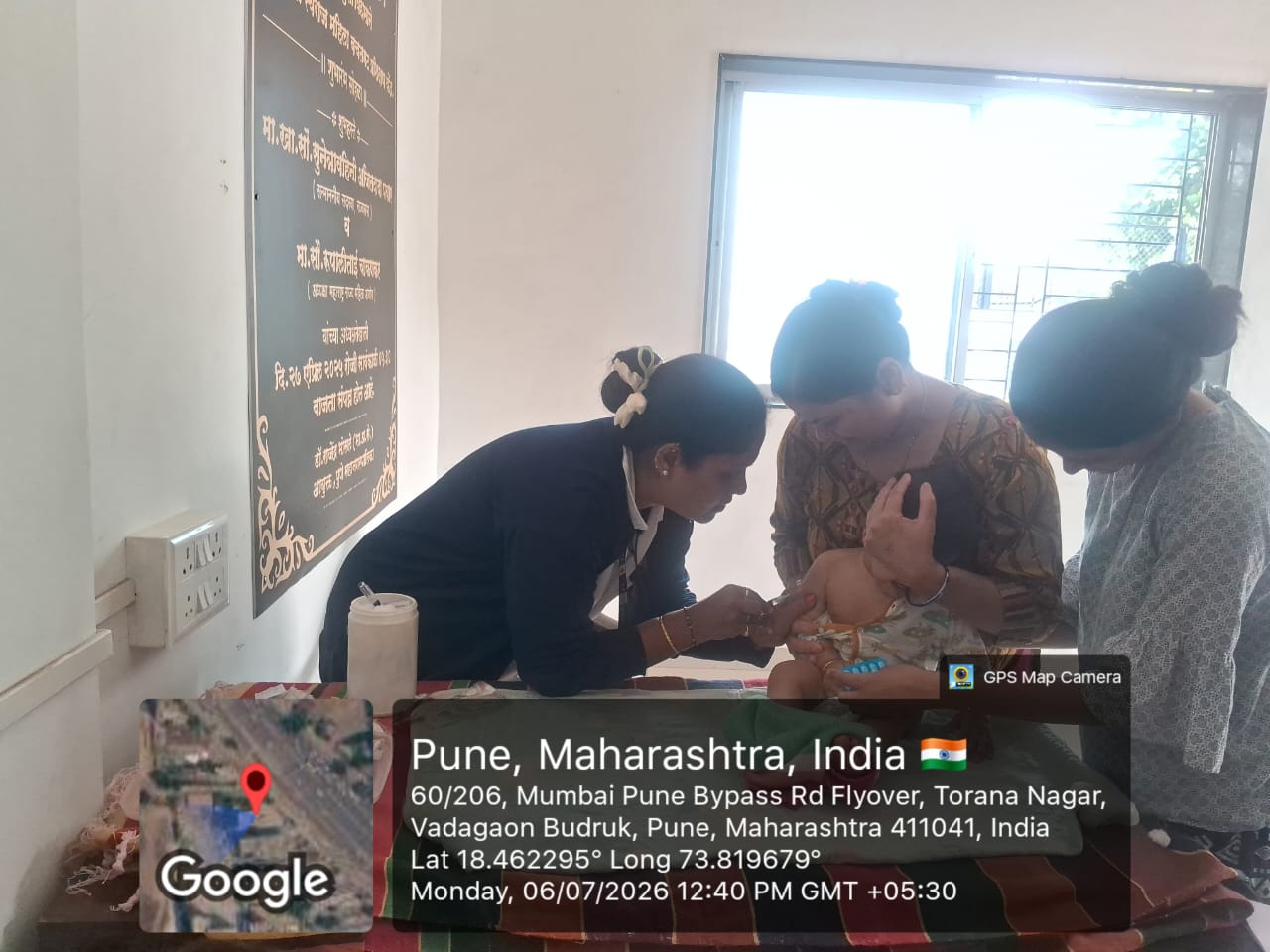 Health worker immunising an infant held by her mother in Vadagaon Budruk, Pune