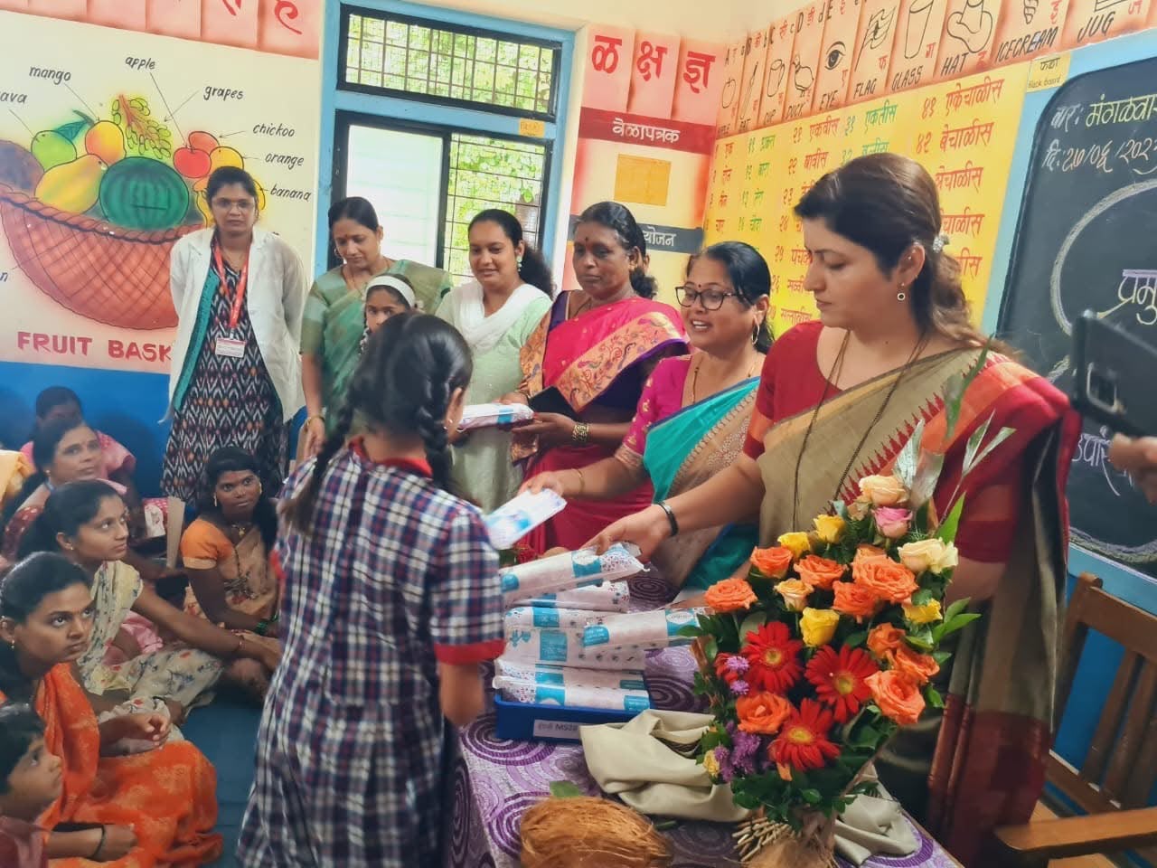 Sanitary napkin packs handed to a schoolgirl inside a primary classroom