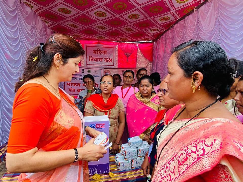 Women collecting free sanitary napkin kits at a village camp