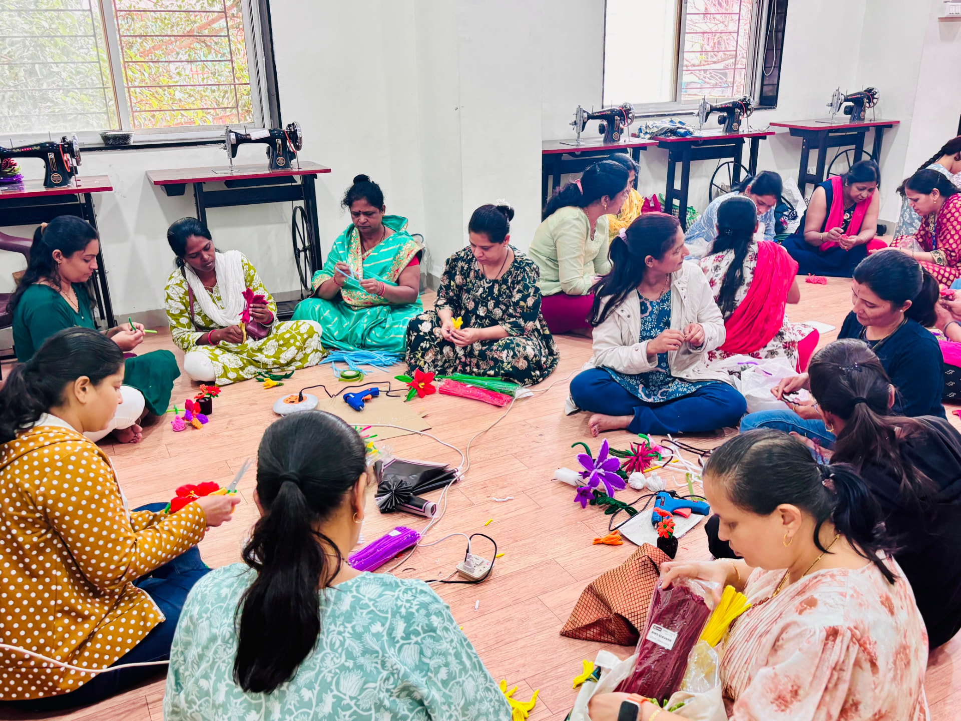 Women working on flowers in a wide circle in the tailoring hall