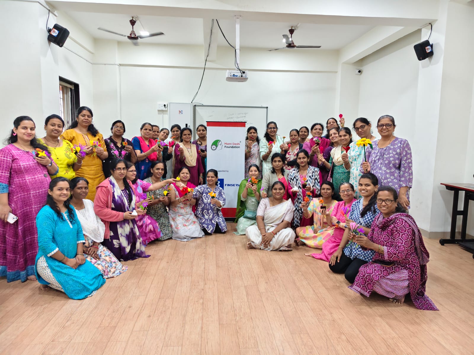 Wide group photograph of workshop participants with their finished flowers